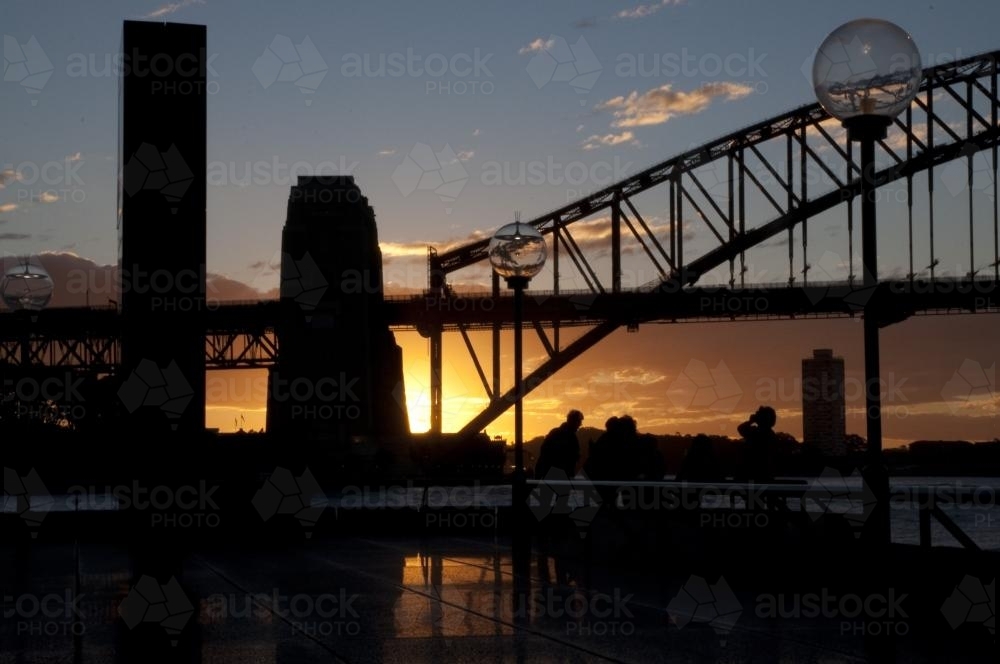 Sun setting behind the south pylon of the Sydney Harbour Bridge - Australian Stock Image