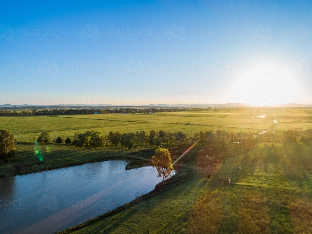 Sun setting in blue sky over rural Australian agricultural landscape   - Australian Stock Image