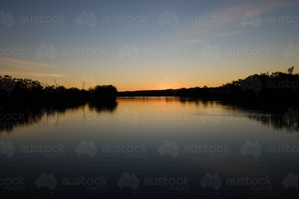 Sun setting over the River Murray in Victoria with calm reflections - Australian Stock Image