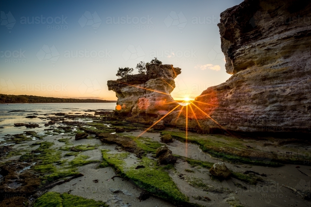 Sun setting through The Hole in the Wall at Jervis Bay - Australian Stock Image