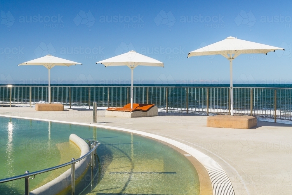 Sun umbrellas around the edge of a swimming pool - Australian Stock Image