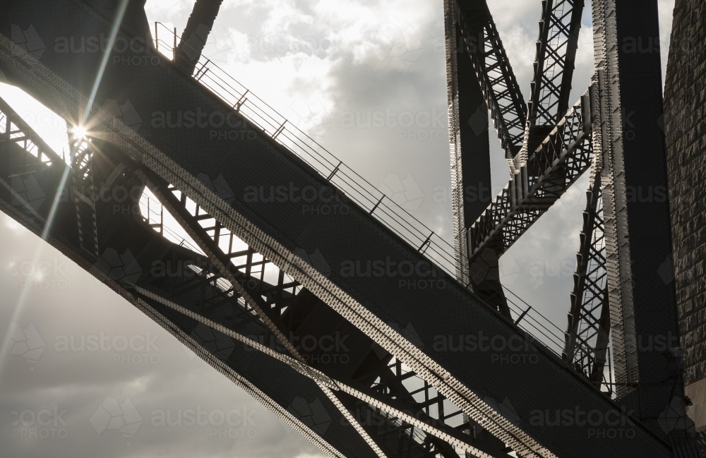 Sunburst through partial structure of Sydney Harbour Bridge against the sky - Australian Stock Image