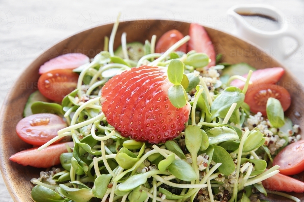 Sunflower sprouts and strawberries salad on wooden bowl - Australian Stock Image