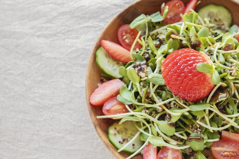 Sunflower sprouts and strawberries salad on wooden bowl - Australian Stock Image