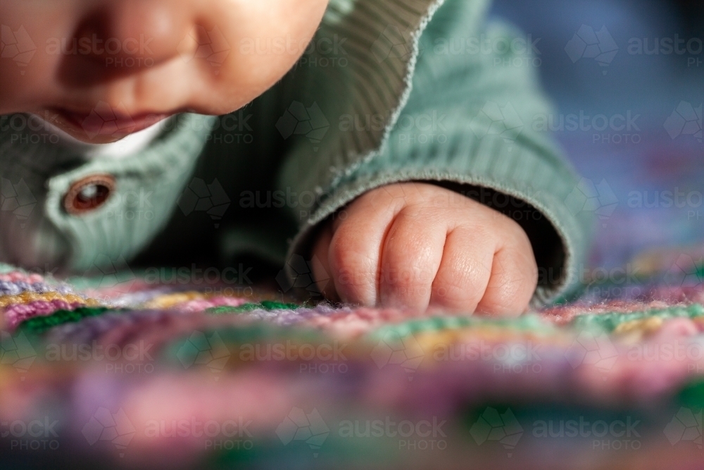 Image of Sunlight falling over baby fingers on blanket close up