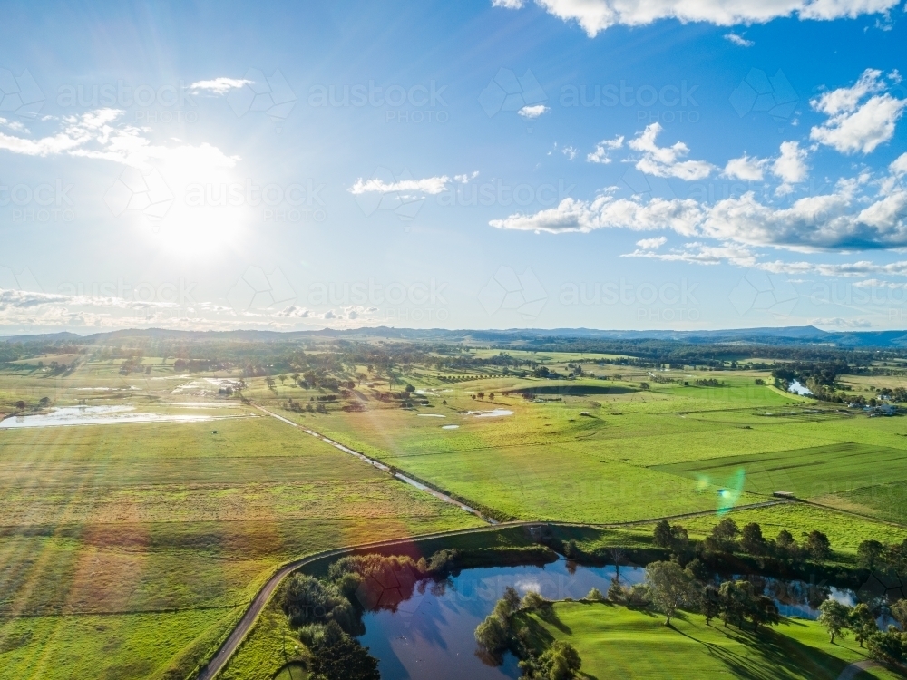 Sunlight over bend in Paterson River with water channel through farmland - Australian Stock Image