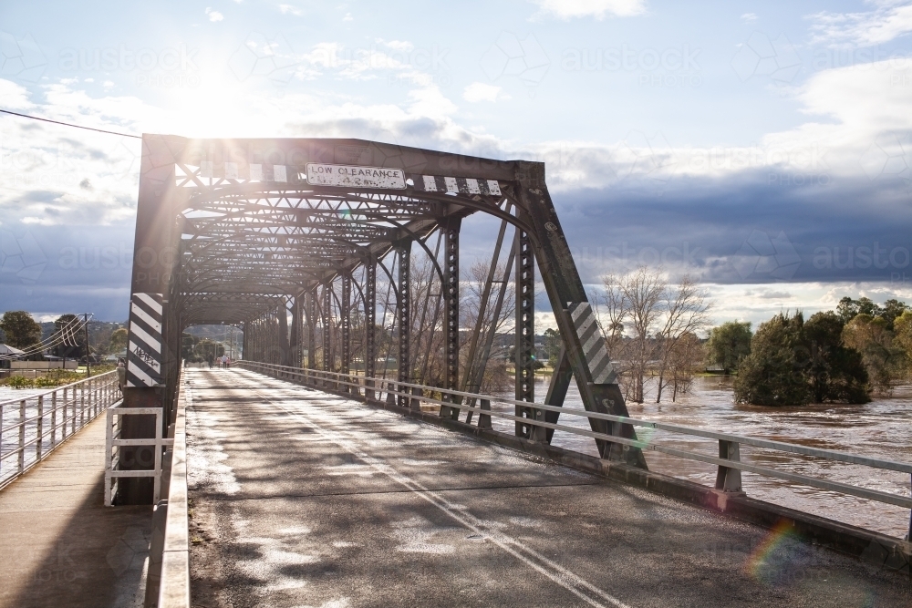 Image of Sunlight over old truss bridge in Singleton with floodwaters ...