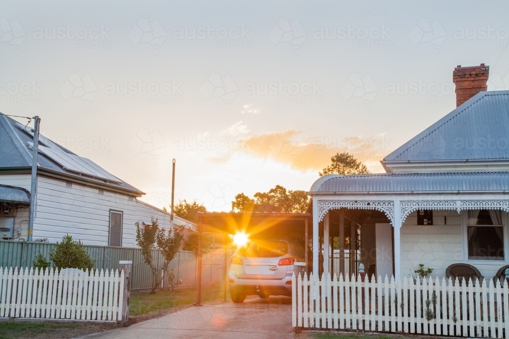 Sunlight shining in lens flare over car parked next to home - Australian Stock Image