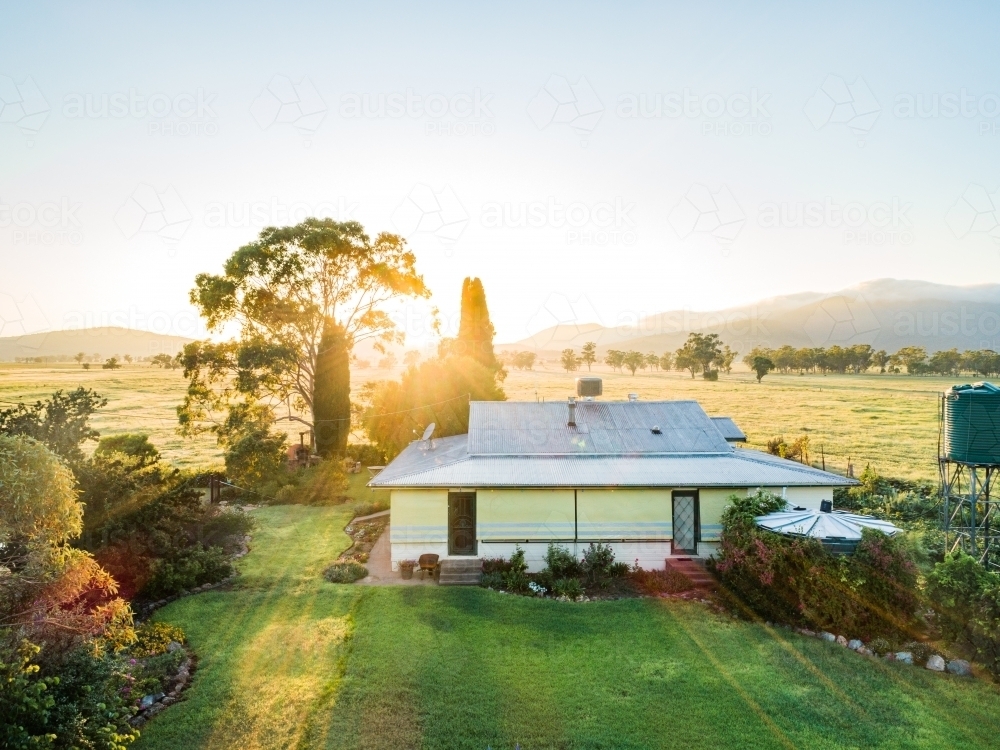 Sunlight shining over farm homestead in morning, grass is green after rain - Australian Stock Image