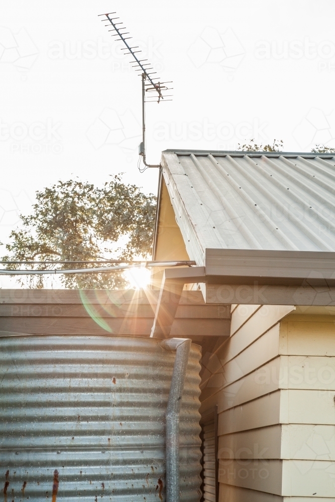 Sunlight shining past shed and rainwater tank - Australian Stock Image