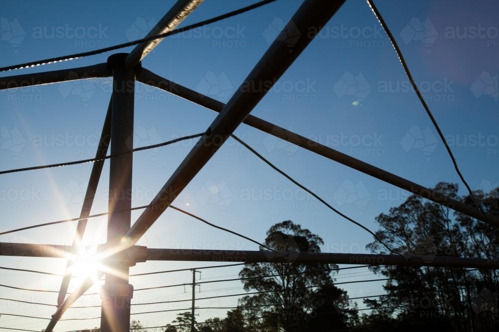 Sunlight shining through a hills hoist washing line silhouetted against sky - Australian Stock Image