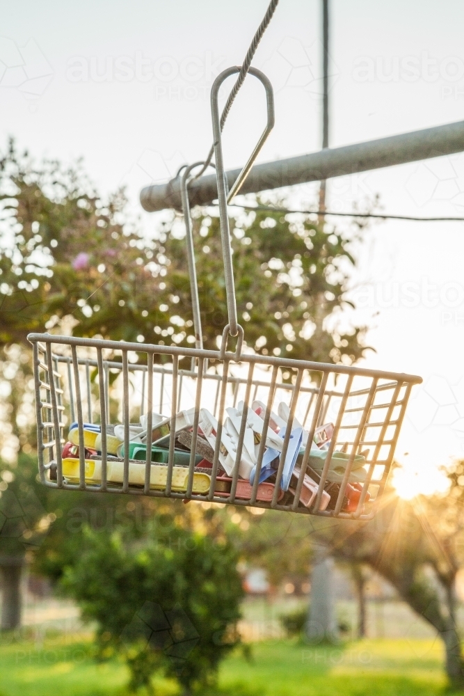 Sunlight shining through peg basket on washing line in backyard of country homestead - Australian Stock Image