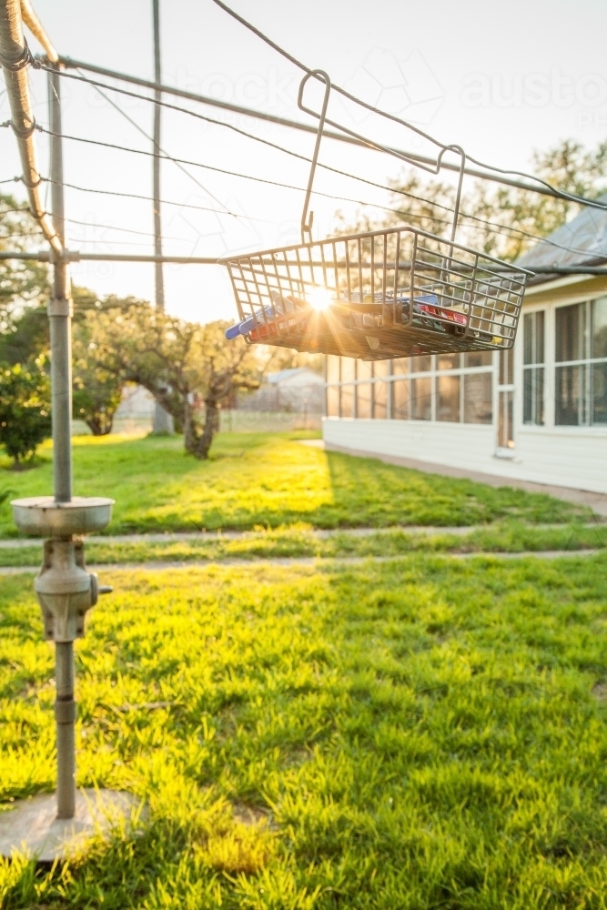 Sunlight shining through peg basket on washing line in backyard of country homestead - Australian Stock Image