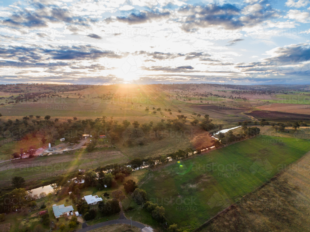 Sunlight streaming over river running through farmland in the Hunter region of New South Wales - Australian Stock Image
