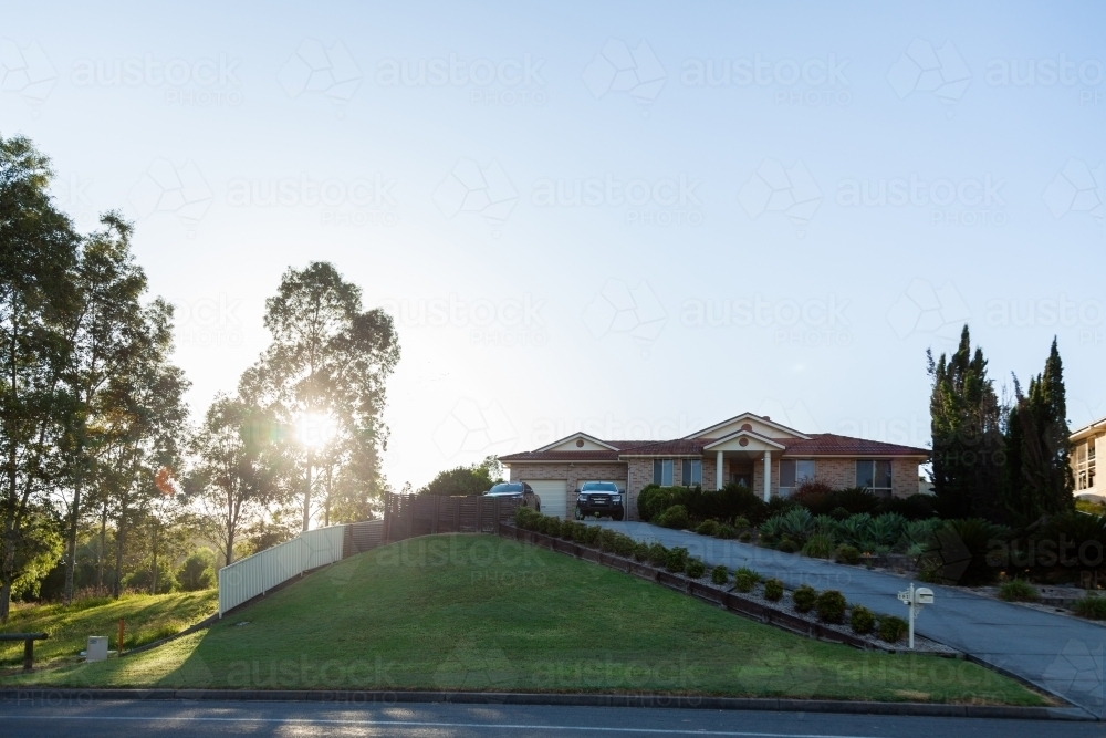 Sunlight through trees with a house beside nature reserve - Australian Stock Image