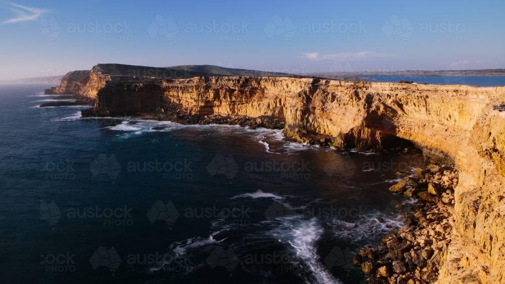 Sunlit cliffs surrounded by ocean - Australian Stock Image