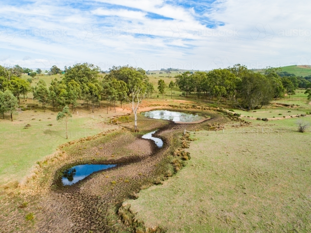 Sunlit creek and dam in rural farm paddock - Australian Stock Image