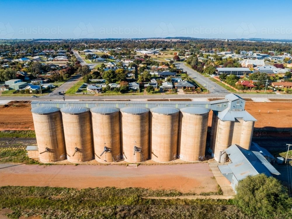 Sunlit grain silos with backdrop of rural town houses of Coolamon - Australian Stock Image