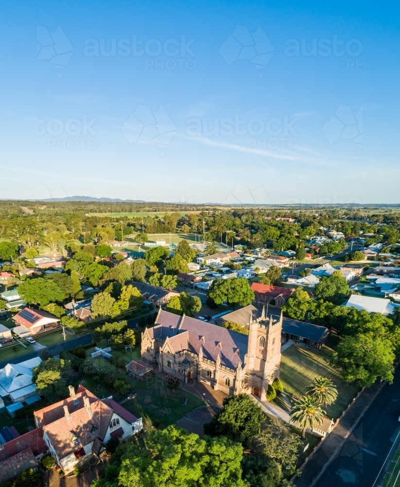 Sunlit historic church building seen from aerial view with big blue sky - Australian Stock Image