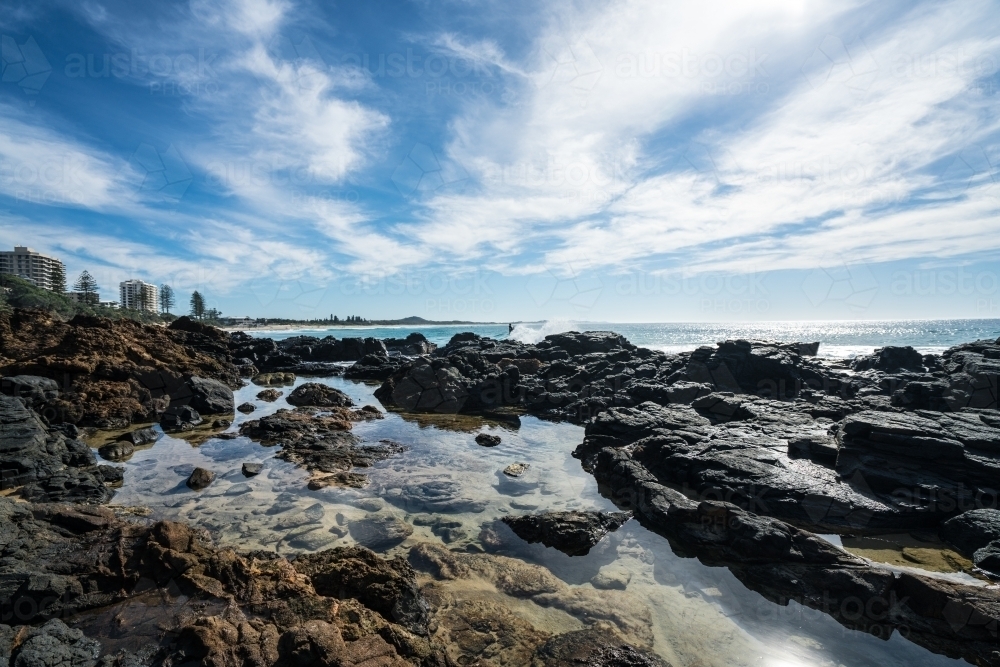 Sunlit rock pools along the coast at Coolum - Australian Stock Image