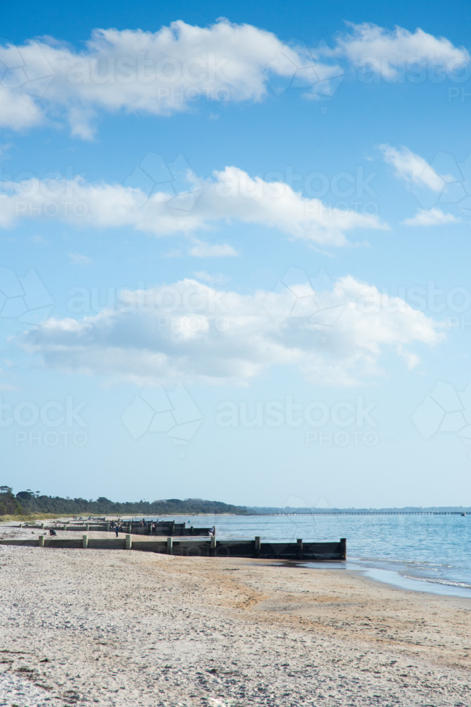 Sunny beach with groynes and blue sky and ocean - Australian Stock Image