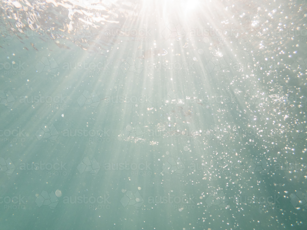 Sunrays underwater with sparkling bubbles in blue pool water  - Australian Stock Image