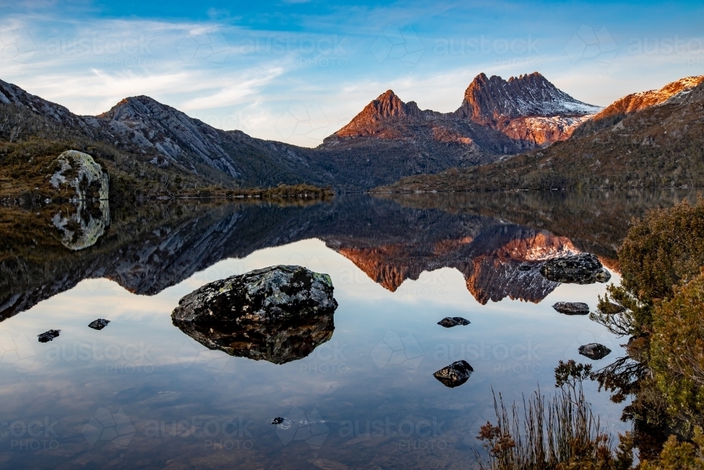 Sunrise looking across reflections in Dove Lake to Cradle Mountain with a dusting of snow - Australian Stock Image