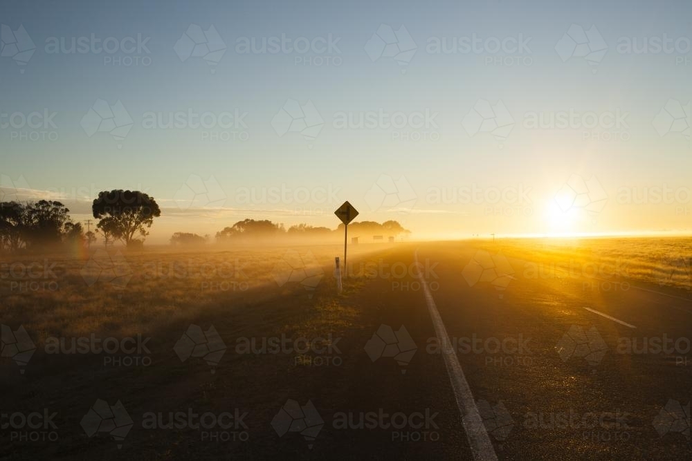 Sunrise on a  regional highway with silhouette road side sign - Australian Stock Image