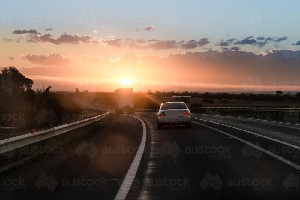 Image of Sunrise on the highway, following a truck and sedan Austockphoto