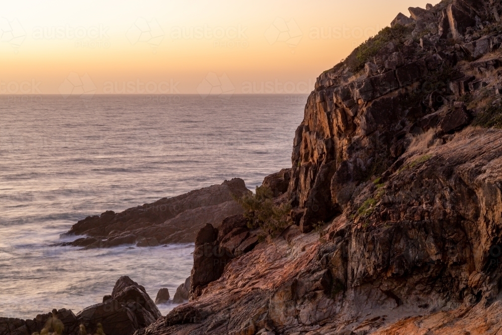 Sunrise over a jagged rocky shore. - Australian Stock Image