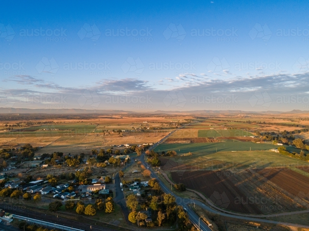 Sunrise over edge of town with road leading out through farm paddock - Australian Stock Image
