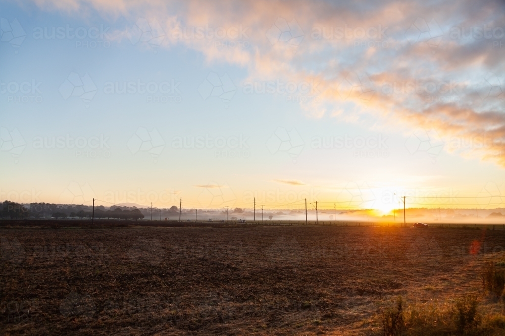 Sunrise over paddocks in Singleton and fog along distant road - Australian Stock Image