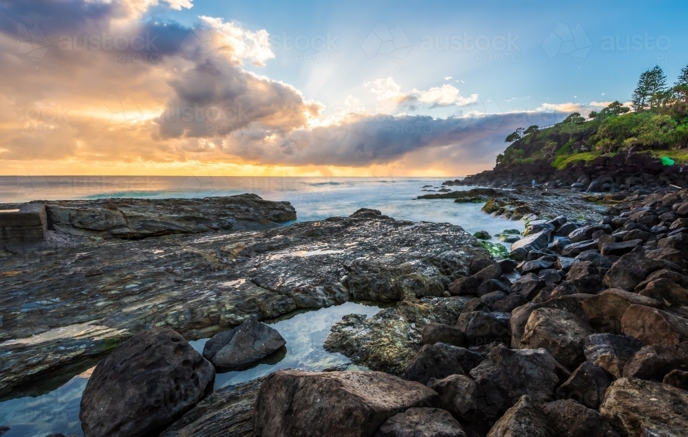 Sunrise over rocky ocean shore - Australian Stock Image