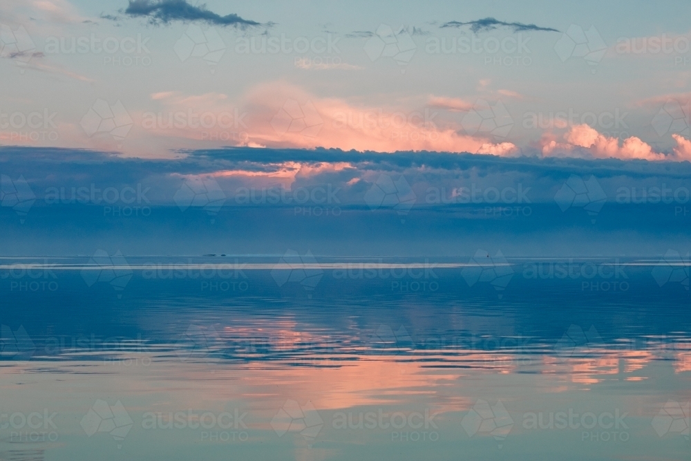 Sunrise reflected on glassy ocean - Australian Stock Image
