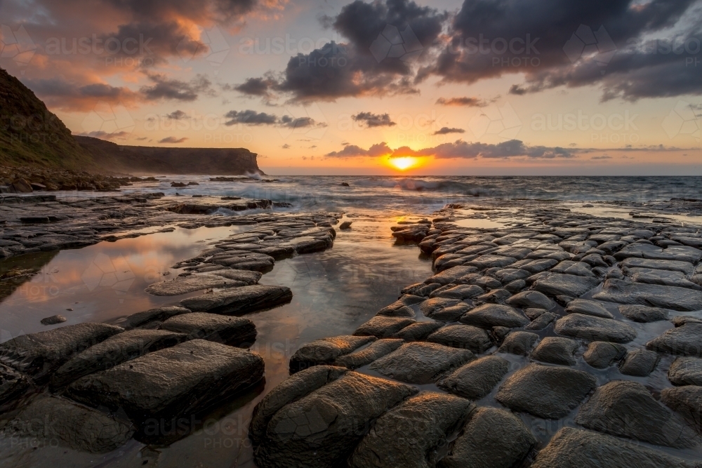 Sunrise sunlight across tessellated rocks Garie Beach - Australian Stock Image
