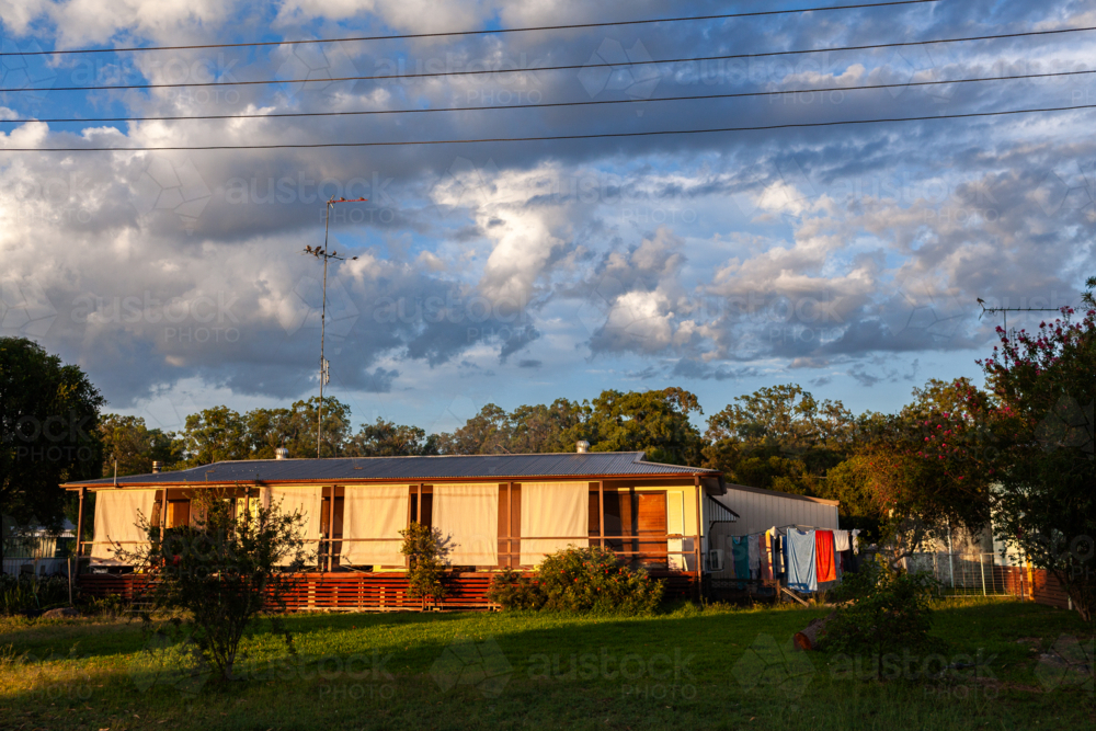 sunrise sunlight on house with privacy screens on verandah and washing line - Australian Stock Image