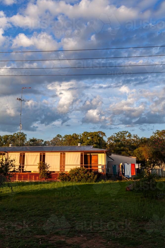 sunrise sunlight on house with privacy screens on verandah and washing line - Australian Stock Image