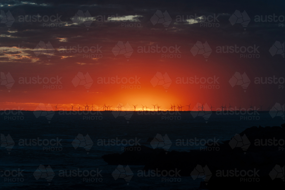Sunset coast with wind turbines and glowing sky - Australian Stock Image