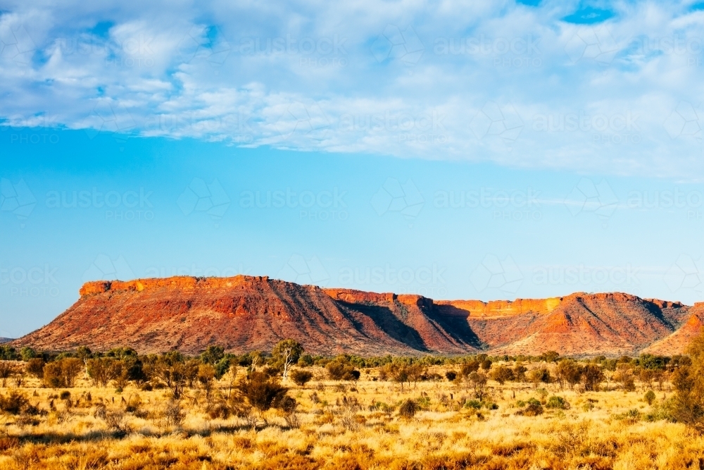 Sunset colours on the rising landforms above the plains near Kings Canyon in Central Australia - Australian Stock Image