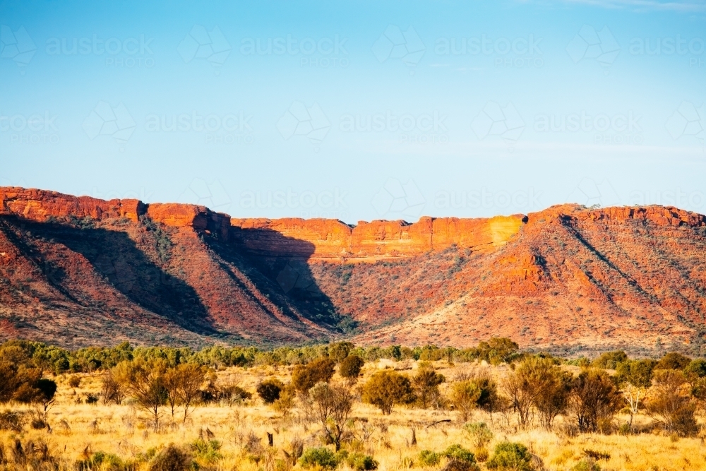 Sunset colours on the rising landforms above the plains near Kings Canyon in Central Australia - Australian Stock Image