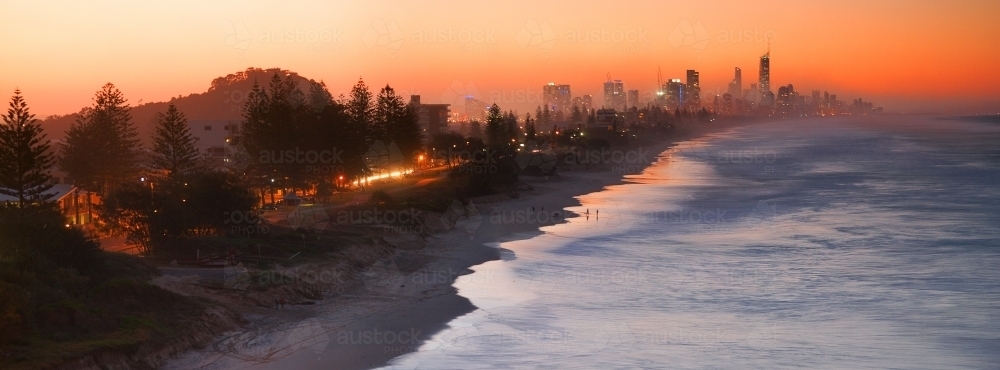 Sunset glow and sea mist shrouds the buildings of populated coastline - Australian Stock Image