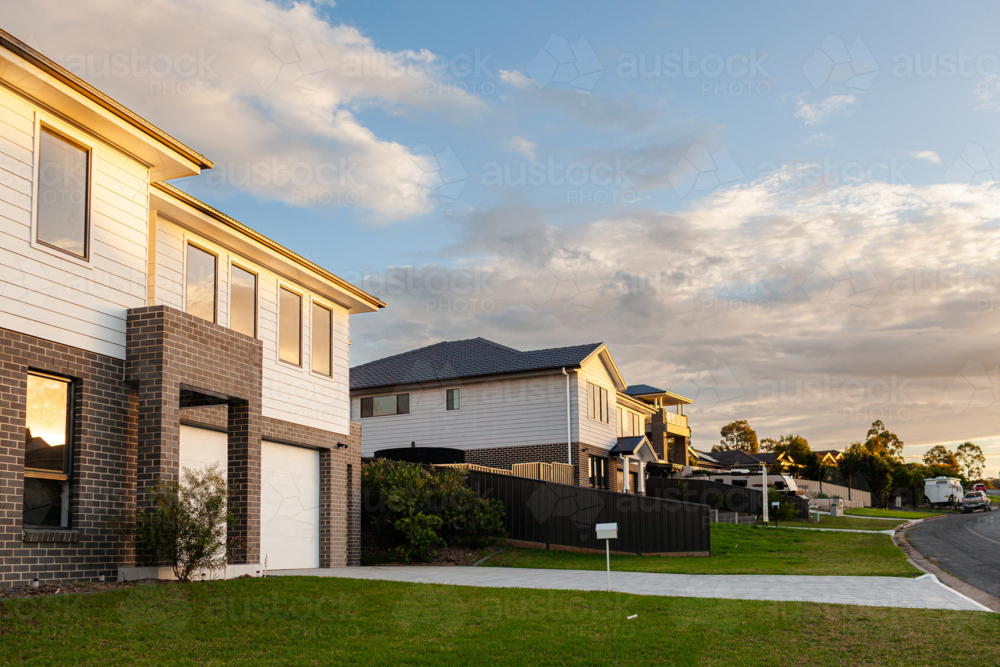 Sunset light on newly built houses along suburban road - Australian Stock Image
