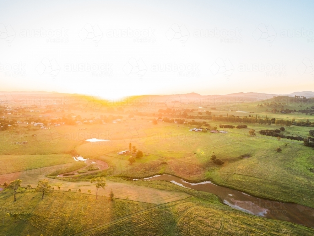 Sunset light over farmland paddock with algae weed covered creek and dam - Australian Stock Image