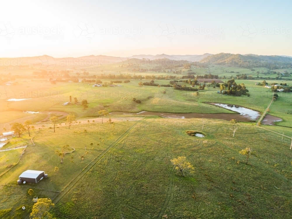 Sunset light over farmland paddock with algae weed covered creek and dam - Australian Stock Image