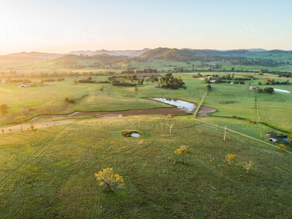Sunset light over farmland paddock with algae weed covered creek and dam - Australian Stock Image