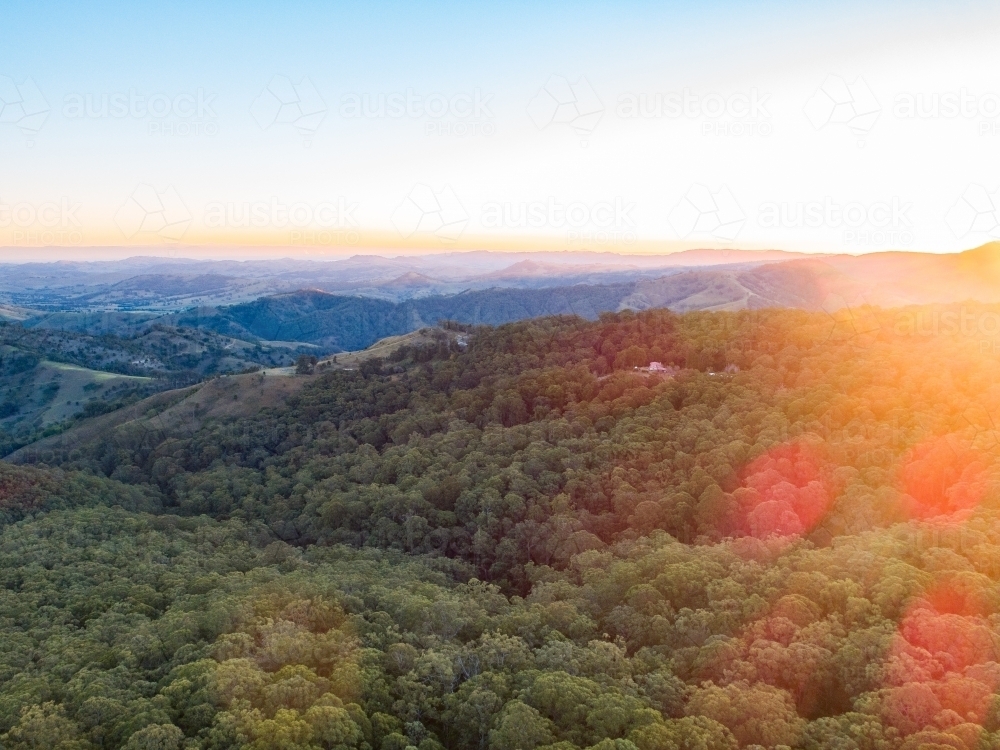Sunset light over mountains covered in trees - Australian Stock Image