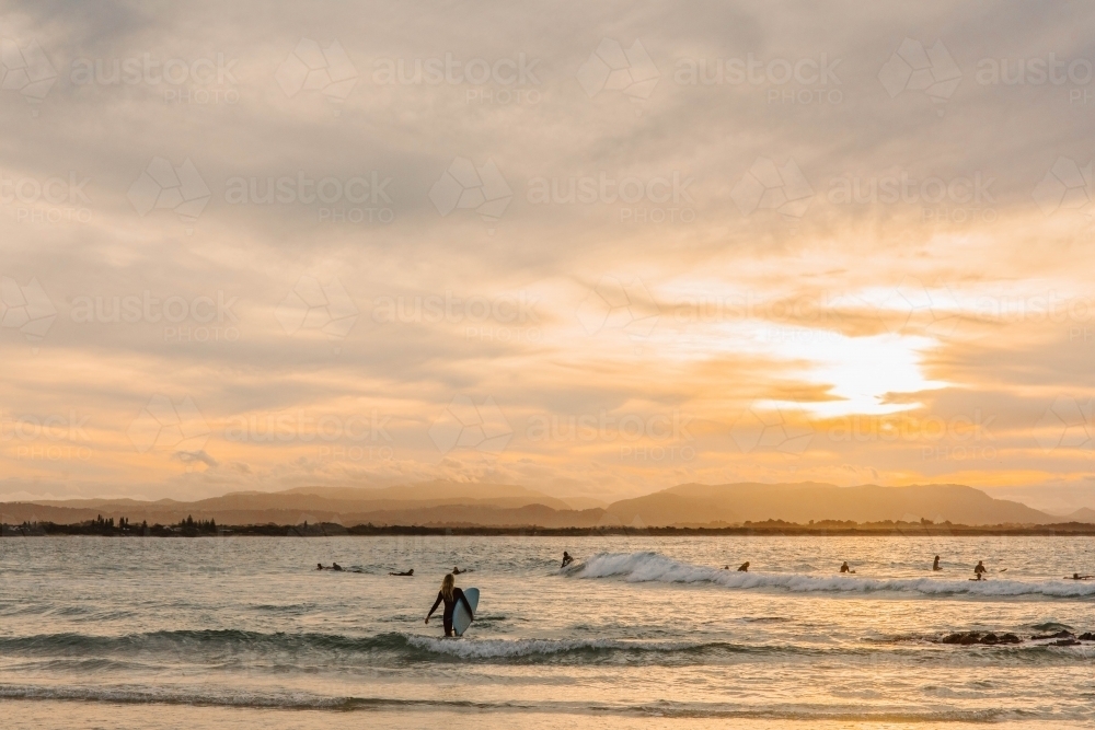 Sunset on the beach with a surfer - Australian Stock Image