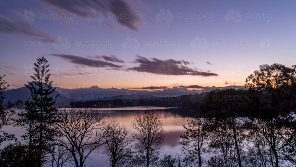 Sunset over lake with trees in foreground - Australian Stock Image