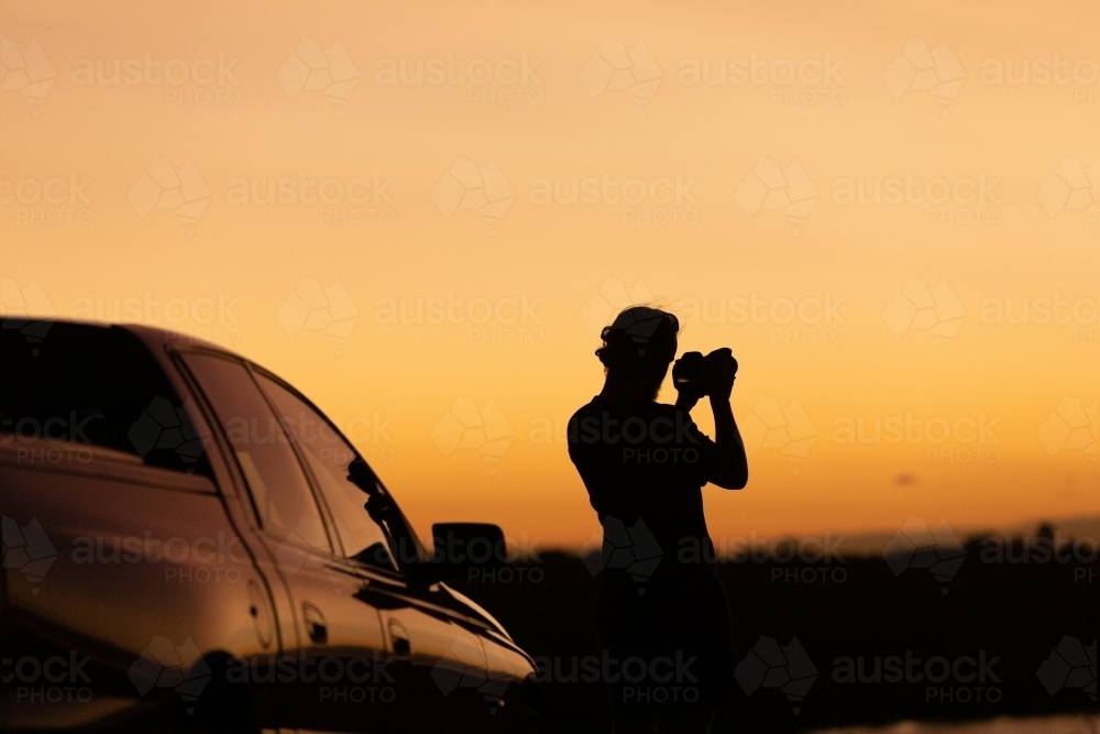 Sunset silhouette of man and car - Australian Stock Image