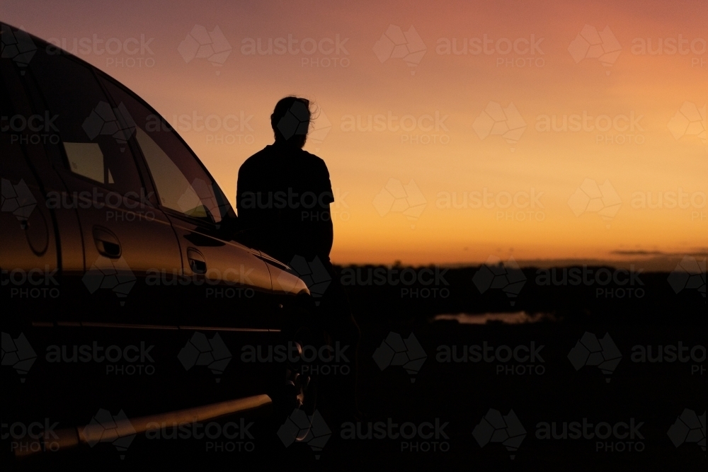 Sunset silhouette of man and car - Australian Stock Image